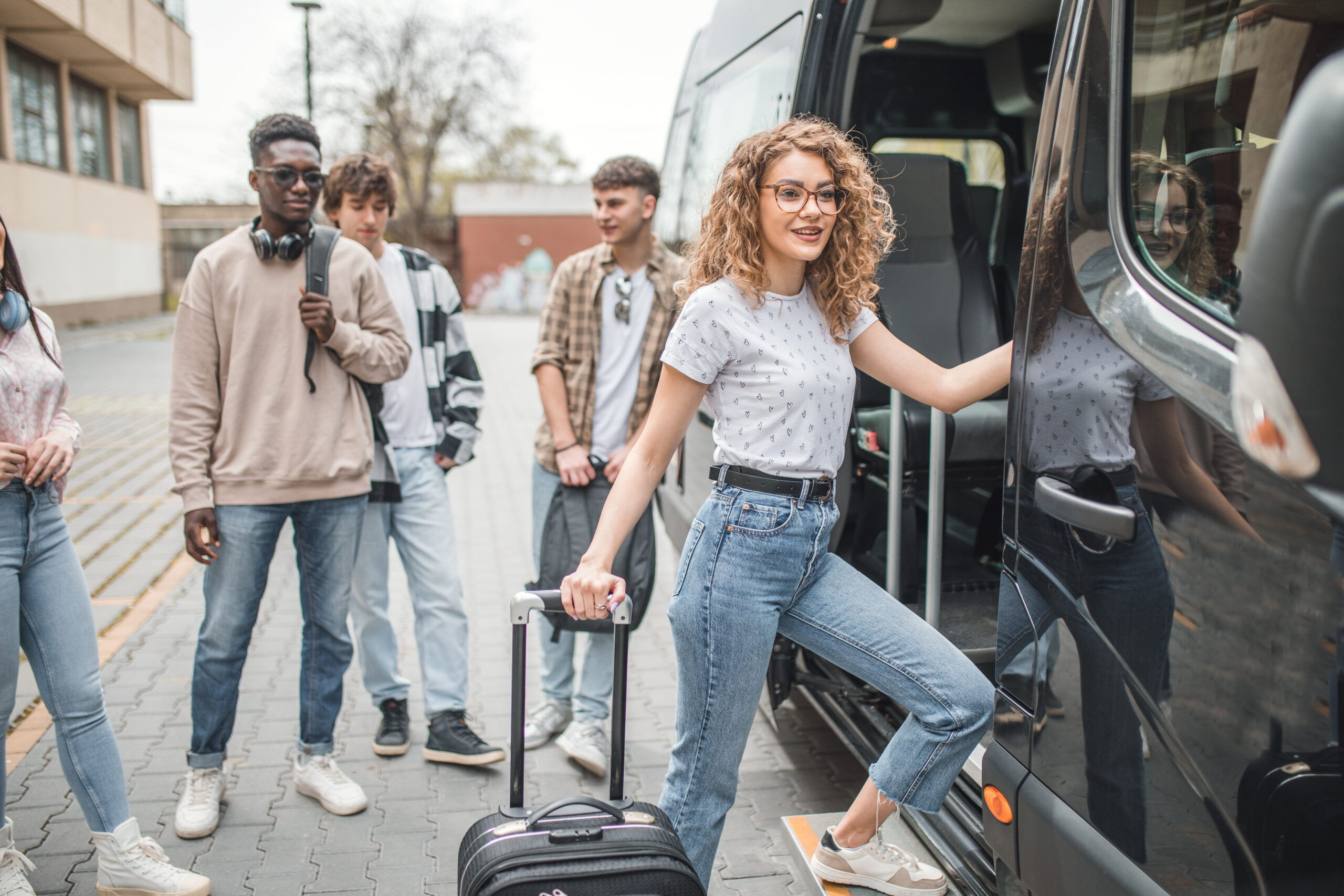 Schülerinnen und Schüler steigen mit Gepäck in einen Reisebus für eine Klassenfahrt ein
